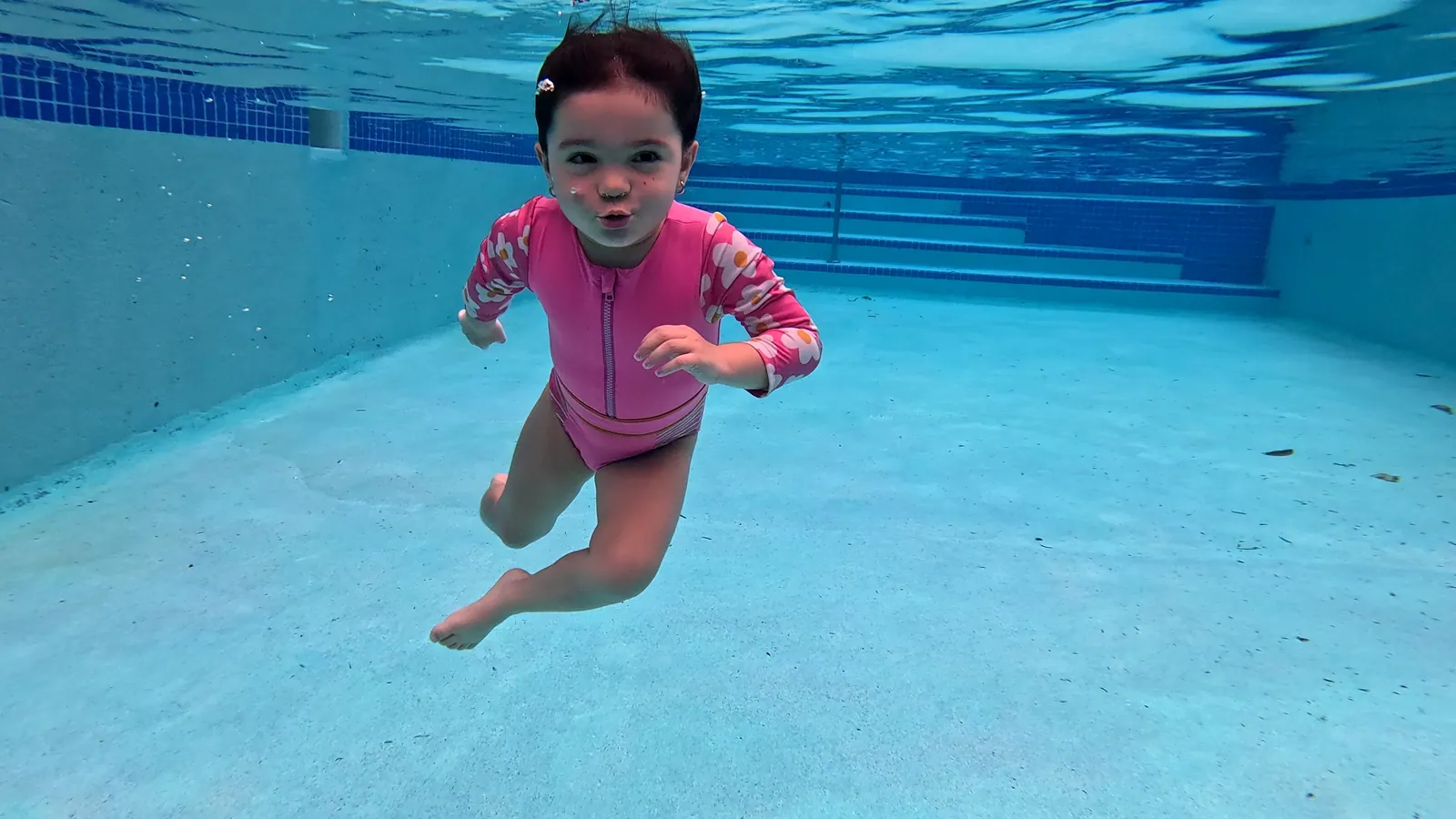 Niña pequeña nadando sola bajo el agua