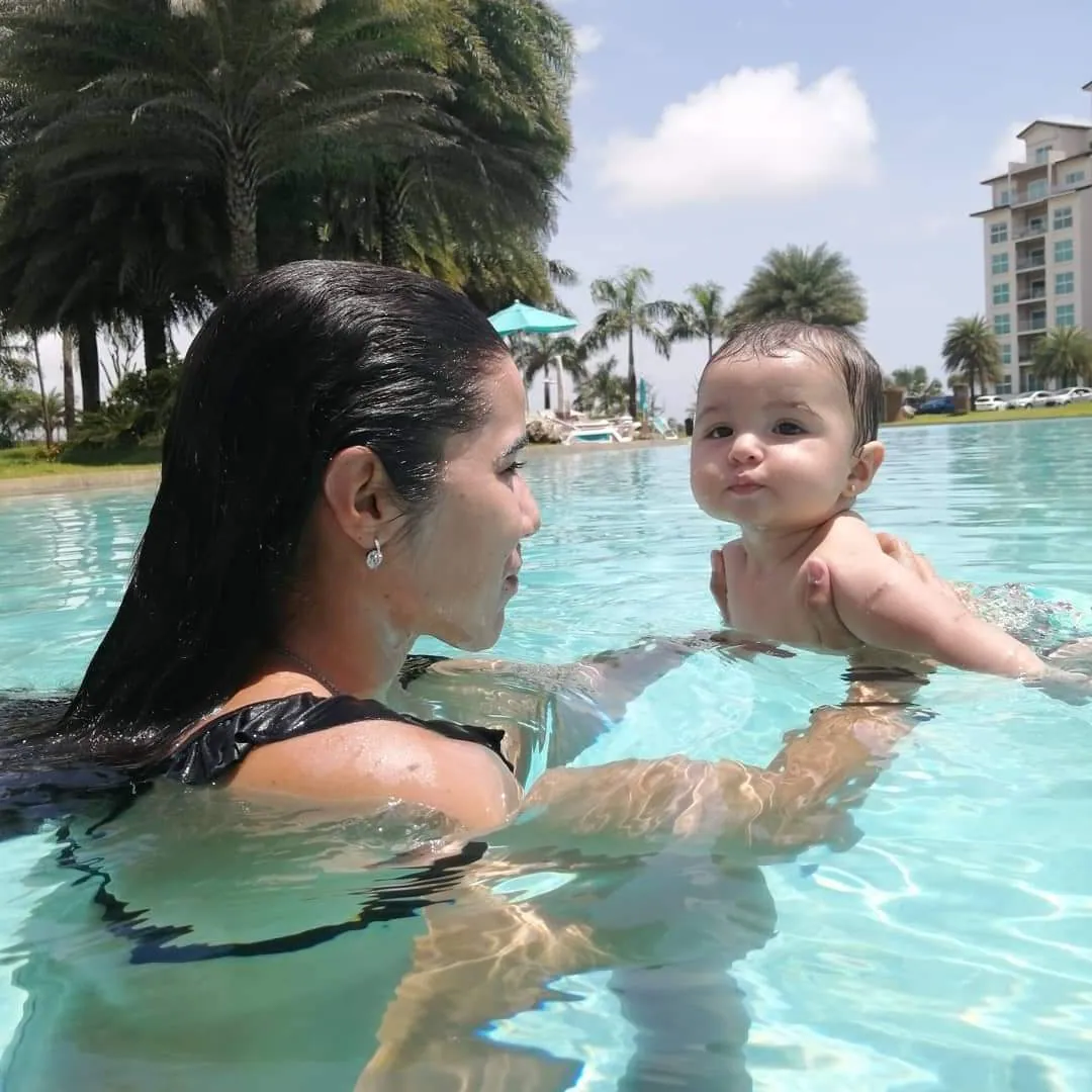 Instructora sosteniendo a un bebé cara a cara en la piscina