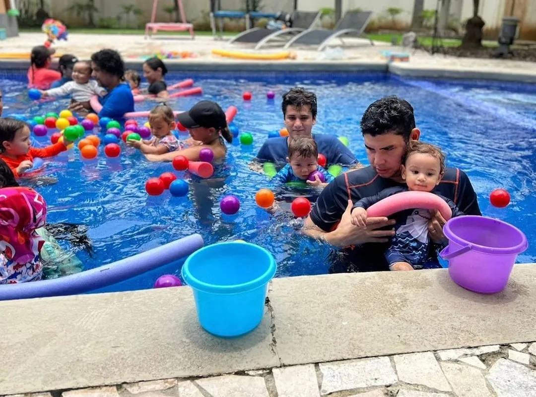 Niños y adultos jugando con pelotas de colores en la piscina