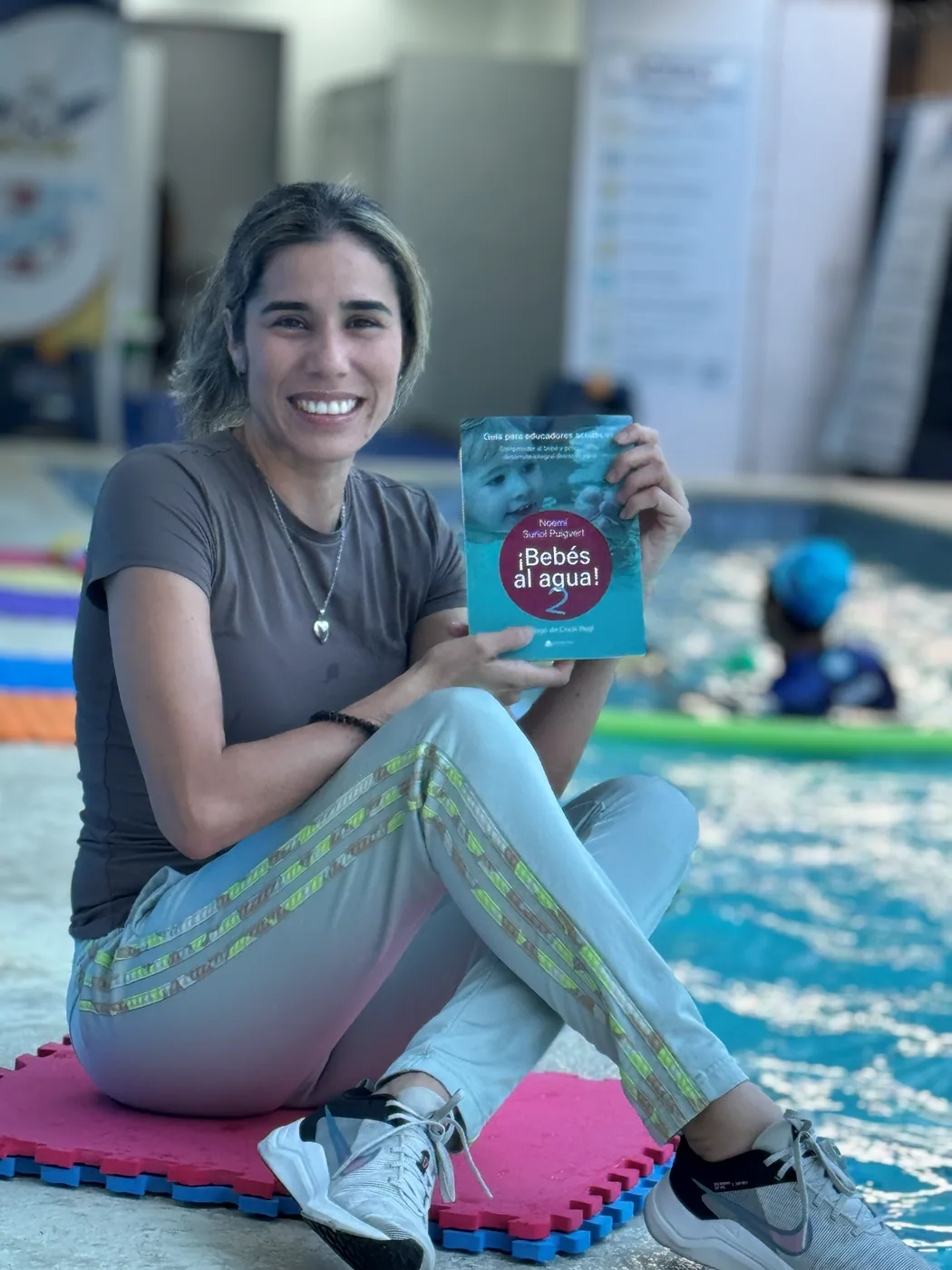 Gissel Giménez junto a la piscina con el libro ¡Bebés al agua! de Noemí Suriol